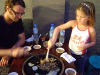 Nikkie en Roos aan het 'gourmetten' (gasfles onder tafel met ijzeren plaat erop)